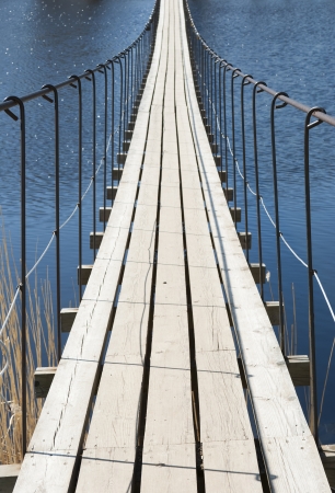 Suspension bridge through the river in a bright sunny dayの写真素材