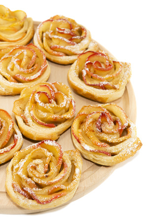 Sweet rolls with apples in the form of roses on wooden board on white isolated backgroundの写真素材