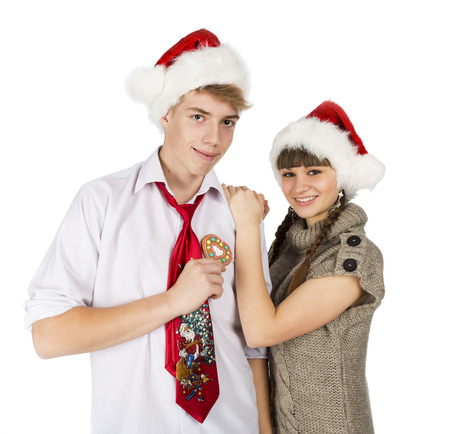 Smiling girl and the guy in red santa caps and gingerbread heart in a hand on a white isolated backgroundの写真素材