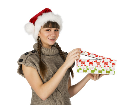 Smiling girl in red santa caps and gift in a hands on a white isolated backgroundの写真素材