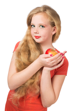 Attractive teen girl in the orange t-shirt holding an red apple in her hand and  looking at camera  Face closeup over white isolated background の写真素材