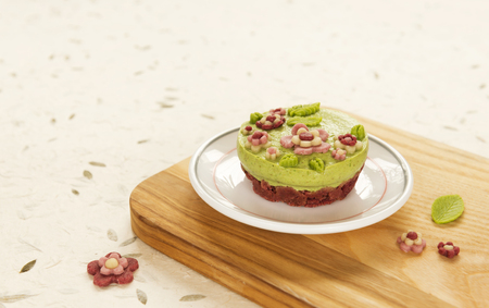 Raw vegan spinach cake with the raw marzipan flowers and leaves on a bright nature paper background. Fully raw food.の写真素材