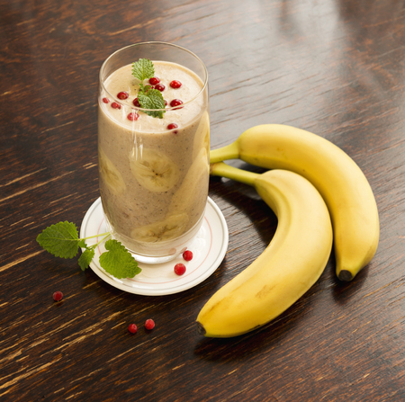 Healthy frozen cowberry and banana smoothie with mint on old vintage table.の写真素材