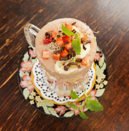 Healthy fresh strawberry and banana smoothie with lucerne sprouts, strawberry pieces, chocolate and mint on old vintage table.の写真素材
