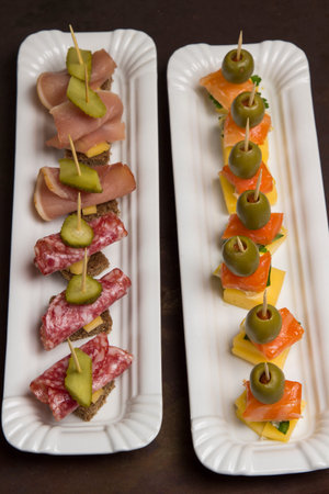 Assortment of canapes with salmon, bacon, cheese, pickles on white plate