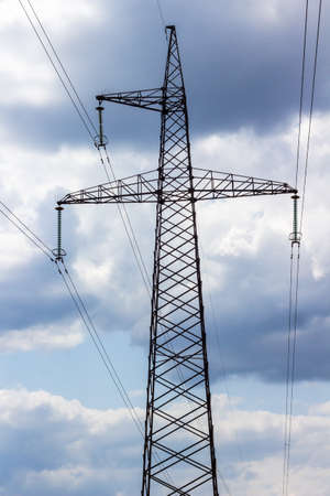 Electric power transmission lines. Metal pylon with wires. Dark sky with clouds.の写真素材