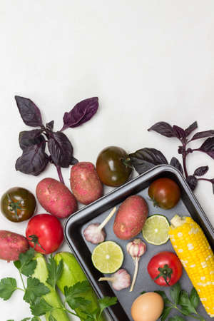 Yellow corn, tomatoes, potatoes on table. Vegetables on pallet. Sprigs of parsley on table. Copy space. White background. Flat layの写真素材