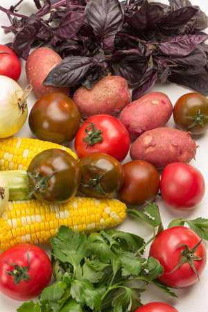 Set of fresh vegetables, potatoes, tomatoes, corn cobs and basil. White background. Flat layの写真素材