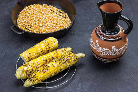 Grilled corn, corn pan and ceramic jug. Black background. Top viewの写真素材