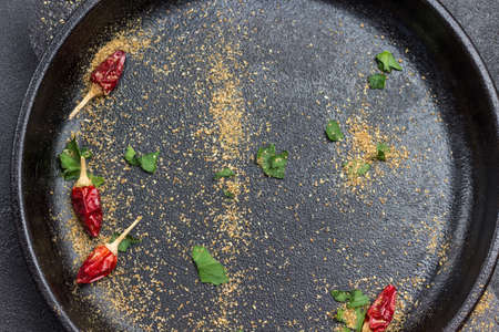 Dry red pepper pods and ground coriander on black background. Allspice, and parsley leaves. Flat layの写真素材