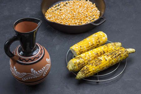 Ceramic jug, grilled corn and pan with corn. Black background. Top viewの写真素材