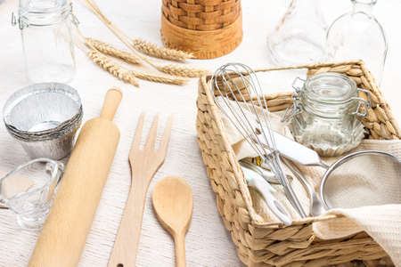 Whisk and sieve in wicker box. Kitchen utensils for making dough. Spikelets of wheat. White background. Top viewの写真素材