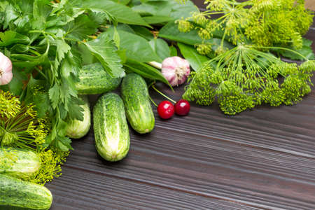 Dill and parsley sprigs, Ñucumbers, garlic and cherry berries. Copy space. Wooden background. Top view.の写真素材