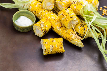 Grilled corn sliced. Grilled corn cobs with leaves. Rusty background. Copy space. Top viewの写真素材