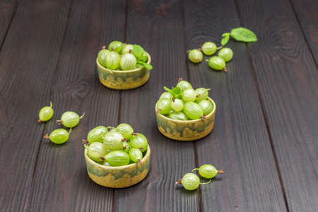 Green bowls with green gooseberries. Dark wooden background. Top viewの写真素材