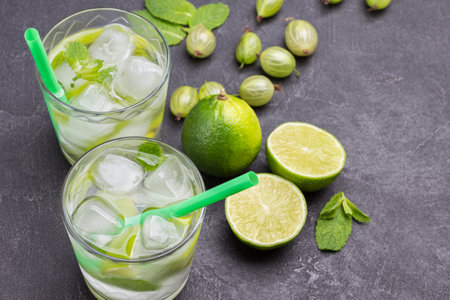 Cooling lemon drink with ice. Straw in glass. Lime on table. Black background. Top viewの写真素材