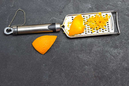Grated orange peel on grater. Black background. Top view. Copy spaceの写真素材