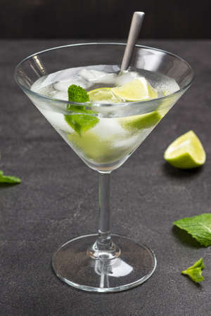 Misted wine glass with lime and ice. Mint sprigs on table. Black background. Top viewの写真素材