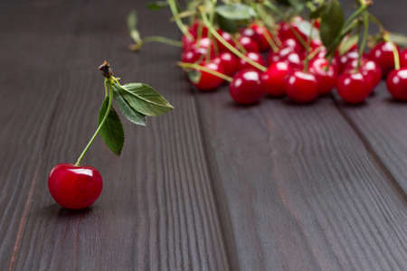 Sprig of cherries with leaves. Bunch of cherries on table. Wooden background. Top view. Copy spaceの写真素材