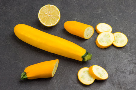 Ripe yellow zucchini, sliced zucchini, half lemon. Black background. Top viewの写真素材