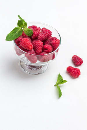 Raspberries in glass bowl. Mint leaves. White background. Copy space. Top viewの写真素材