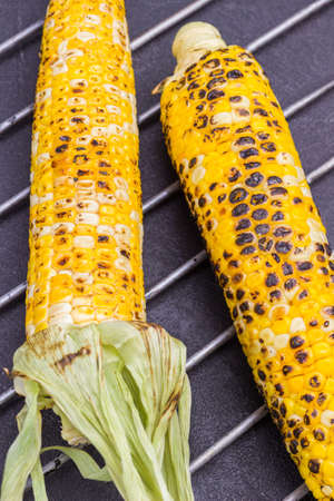 Two cobs of grilled corn on metal grill. Black background. Top viewの写真素材