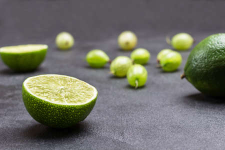 Lime halves and gooseberry berries on black background. Close up. Natural protection against colds.の写真素材