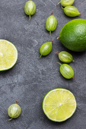 Lime halves and gooseberry berries on black background. Top view