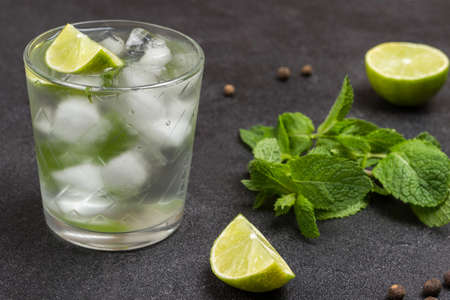 Summer refreshing drink with lime, mint and ice. Lime slices and mint leaves on table. Black background. Top viewの写真素材