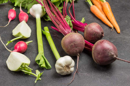 Fresh vegetables set. Beets with tops, garlic with stalks, carrots and kale turnip cabbage. Black background. Top view.の写真素材