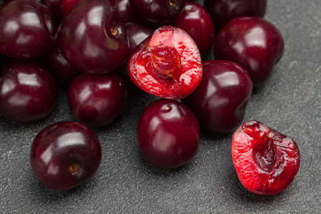 Heap of ripe cherries. Half cherry, pulp and kernel of cherry. Close up. Black background. Top view.の写真素材