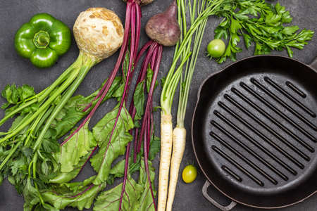Celery, parsley, beets with tops. Green pepper. Empty frying pan. Flat lay. Black backgroundの写真素材