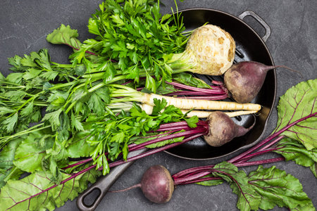 Celery, parsley, beets with tops in pan. Beets on table. Flat lay. Black background