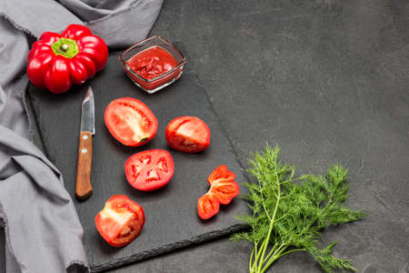 Chopped celery stalks, green tomatoes and dill on gray plate. Kitchen knife. Copy space. Black background. Top viewの写真素材