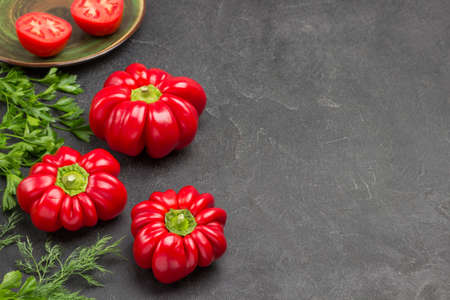 Three red peppers and parsley and dill. Copy space. Black background. Top viewの写真素材
