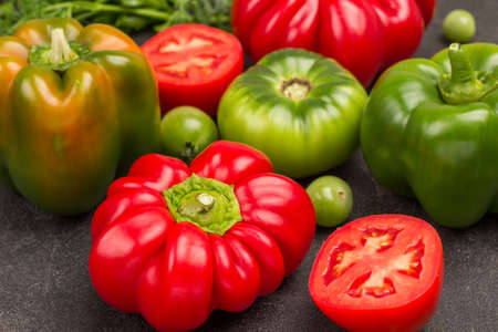 Red and green tomatoes and peppers close-up. Black background.の写真素材