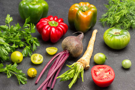 Parsley root, beets and tomatoes. Dill and parsley sprigs. Black background. Top viewの写真素材