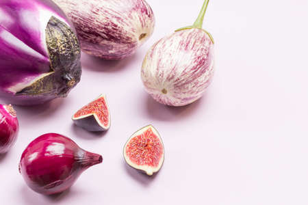 Purple eggplant, two striped eggplant, blue onion and fig halves on table. Copy space. Top view. White backgroundの写真素材