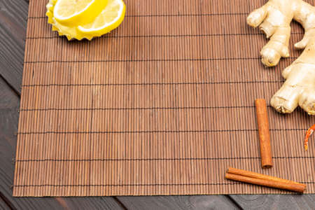 Ginger root and cinnamon sticks on table. Lemon wedges in bowl. Copy space. Wooden background. Top viewの写真素材