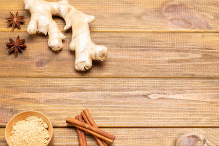 Ginger root and cinnamon sticks on table. Dry ginger powder in bowl. Wooden background. Top view. Copy spaceの写真素材