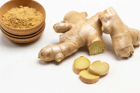 Raw ginger root. Dry ginger powder in bowl. Close-up. White background.の写真素材