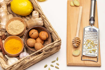 Walnuts, garlic, ginger root and spices in wicker basket. Grater and chopped ginger root. White background. Flat lay.の写真素材