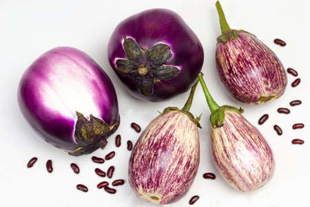 Purple and striped eggplants on table. Bean seeds. Flat lay. White background.の写真素材