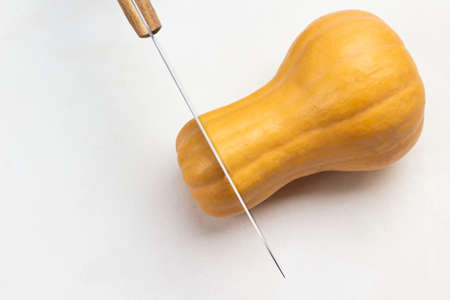 Knife cuts a whole pumpkin. Copy spase. White background. Top view.の写真素材