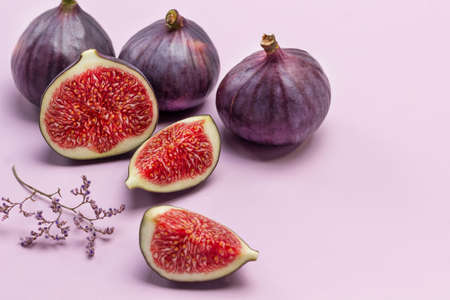 Whole purple figs and Fig halves. Ripe fruit pulp. Copy space. Pink background.の写真素材