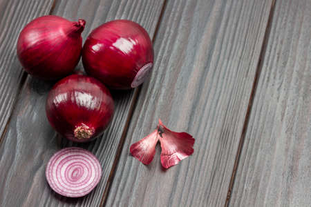 Three purple onion heads and husks on table. Dark wooden background. Top view. Copy spaceの写真素材