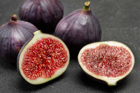 Two halves of fig and Whole purple figs. Ripe fruit pulp. Close up. Black background.の写真素材