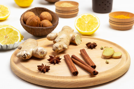 Cinnamon sticks, ginger root and star anise on cutting board. Lemon halves and walnuts. White background. Top viewの写真素材