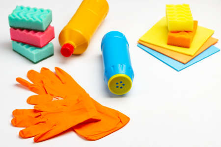 Multi-colored items for cleaning the apartment. Rubber orange gloves, blue bottle of powder, rags and sponges. White background.の写真素材