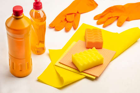 Bottle of orange liquid, yellow sponge, and yellow rag. Rubber orange gloves. Household chemicals for cleaning the apartment. White background. Top viewの写真素材